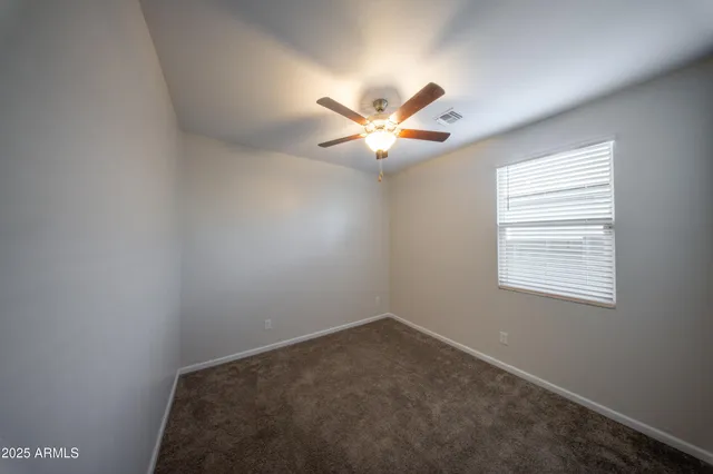 an empty room with a window and a fan
