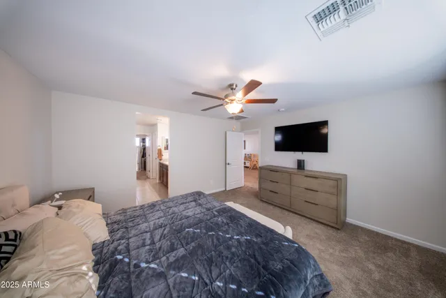 a bedroom with a bed and a flat tv screen on dresser