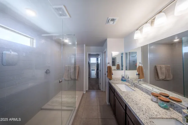 a bathroom with a granite countertop sink a mirror and a shower