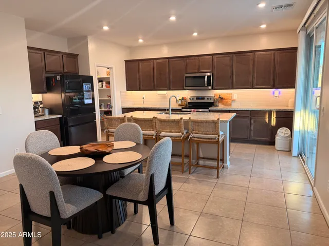 a kitchen with a dining table chairs and refrigerator