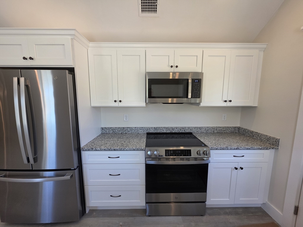 87 Acapesket Road, Unit 2B Falmouth, MA 02536 - Photo 4 of 17 a kitchen with white cabinets and stainless steel appliances