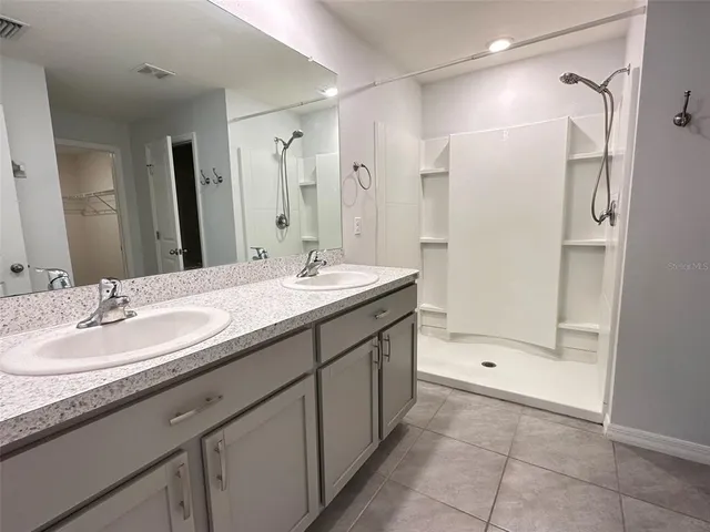 a bathroom with a double vanity sink mirror and shower