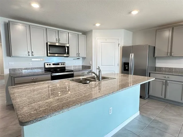 a kitchen with stainless steel appliances granite countertop a sink a stove and a refrigerator