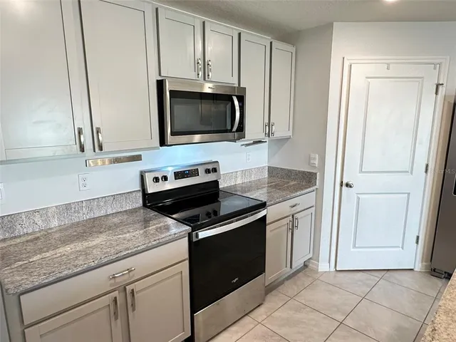 a kitchen with granite countertop white cabinets and stainless steel appliances