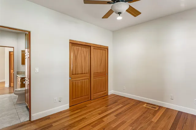 an empty room with wooden floor cabinet and windows