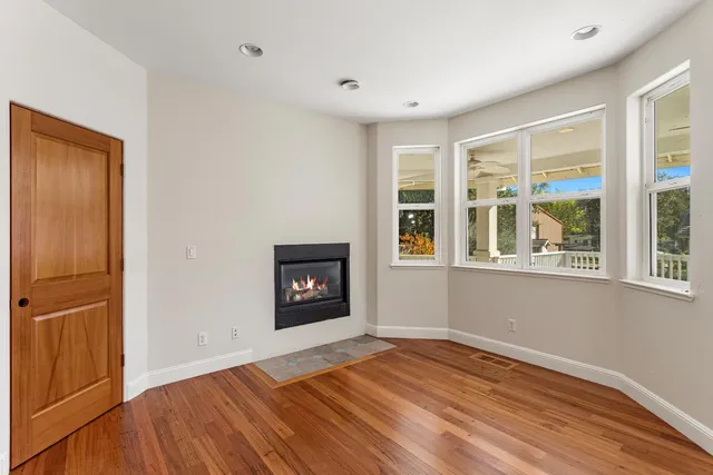 an empty room with windows a fireplace and wooden floor