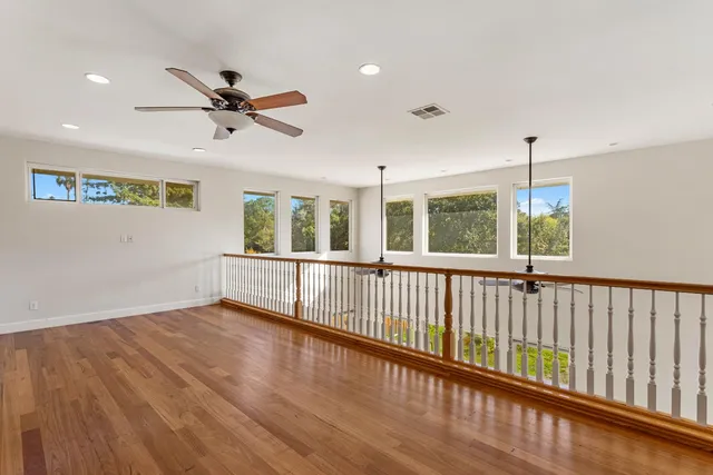 a view of a room with wooden floor fan and windows