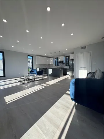 a living room with stainless steel appliances furniture a rug and a kitchen view