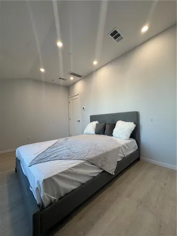 a spacious bedroom with a bed and a lamp with the table