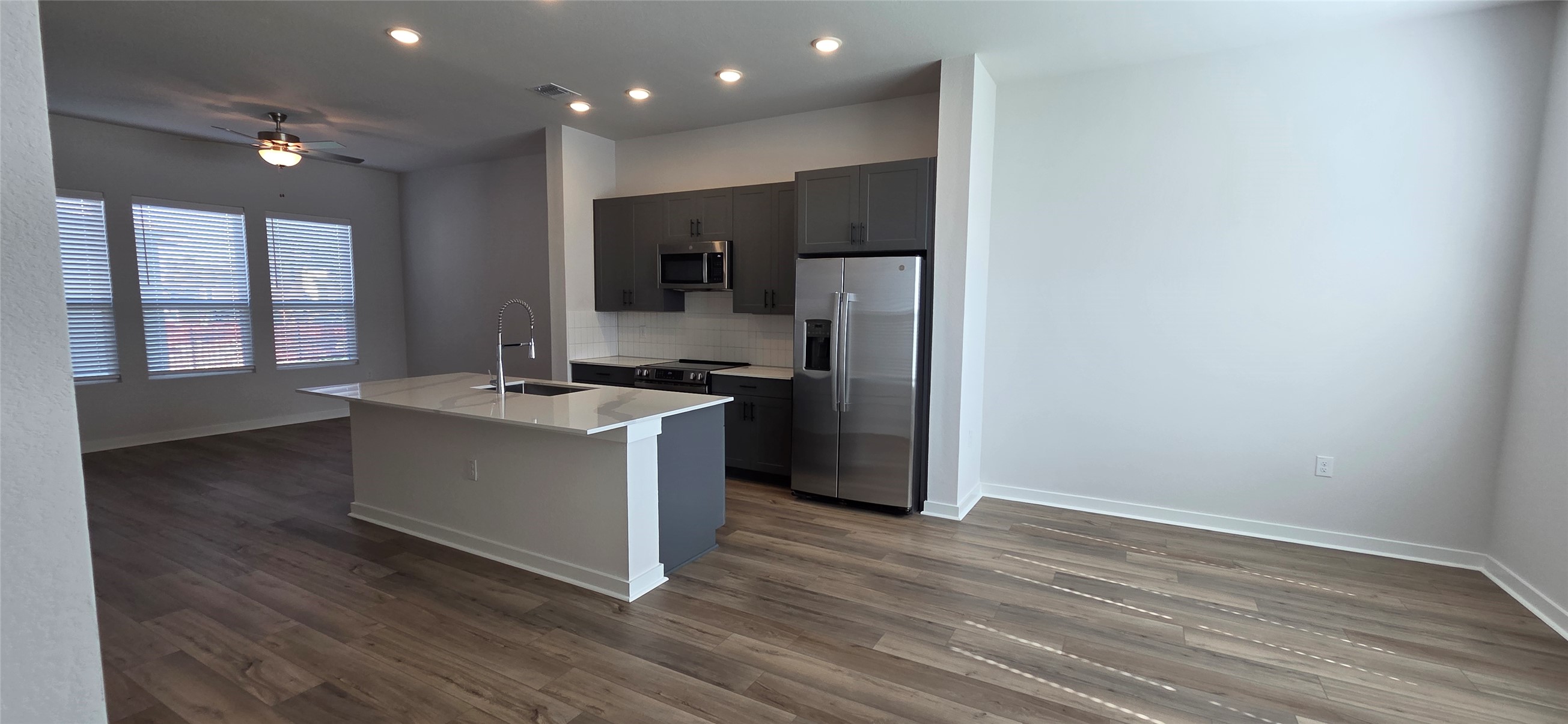 8107 Wilder Road Austin, TX 78736 - Photo 5 of 35 Modern kitchen with an inviting island and elegant wood flooring connects to a sun-filled living area.