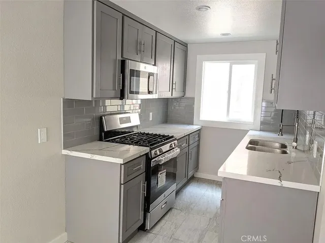 a kitchen with granite countertop a sink a stove and wooden cabinets