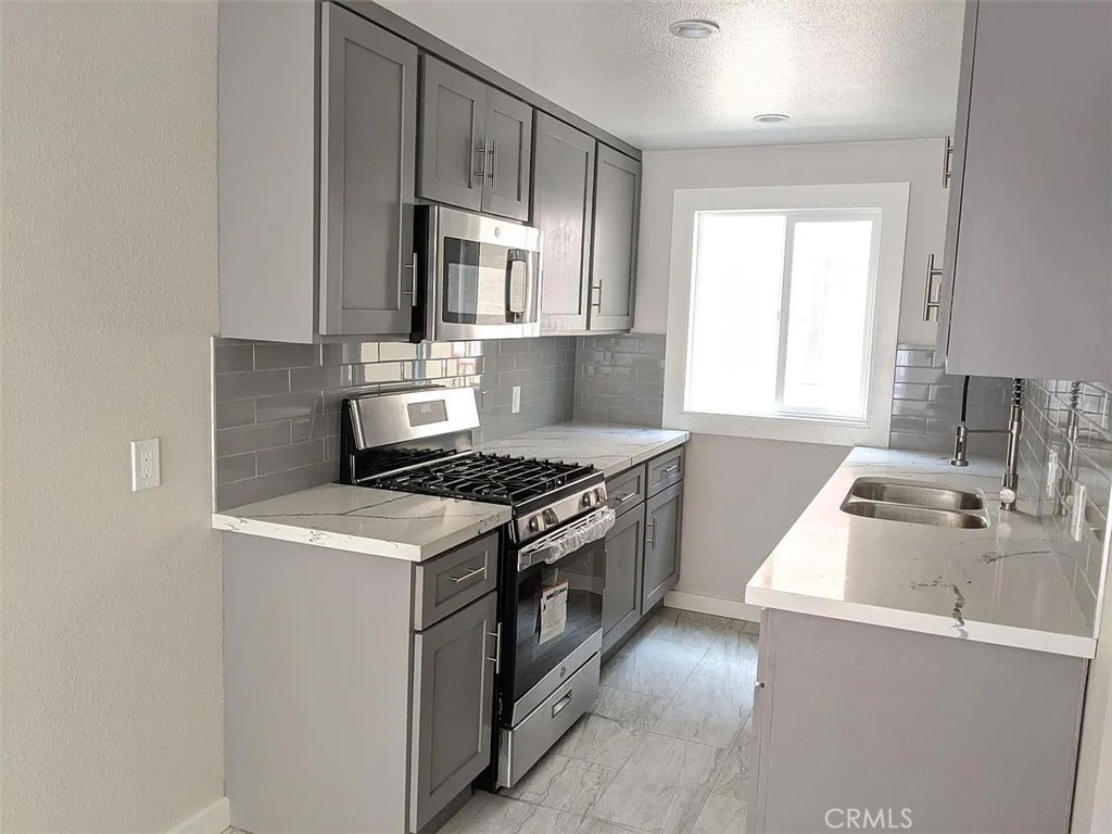 7370 Neo Street Downey, CA 90241 - Photo 21 of 38 a kitchen with granite countertop a sink a stove and wooden cabinets