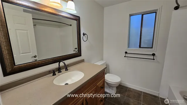 a bathroom with a granite countertop toilet sink and mirror