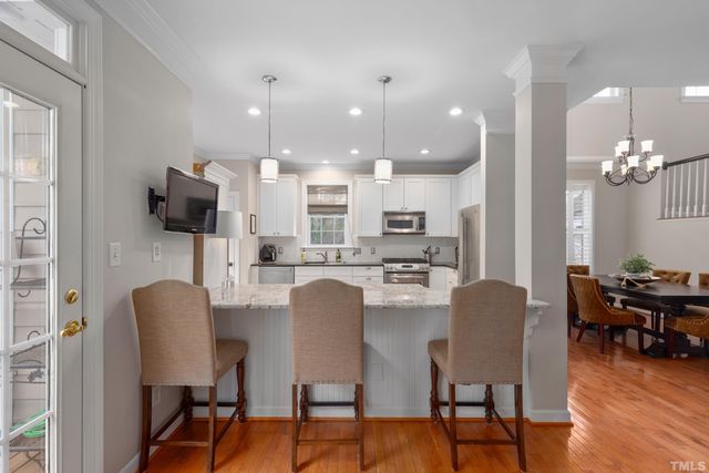 a dining room with furniture a chandelier and a kitchen