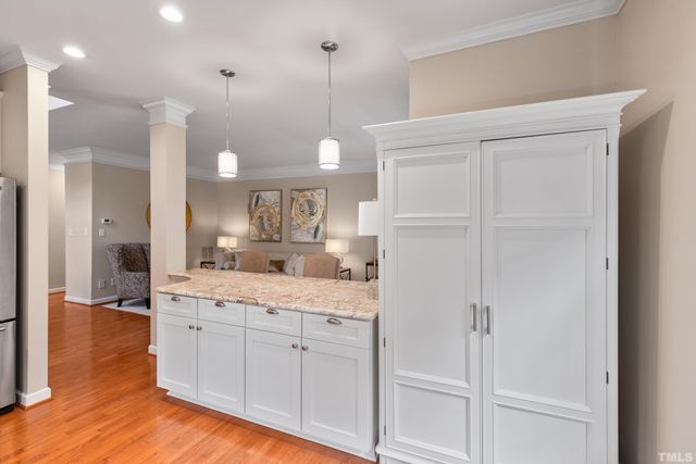 a large white kitchen with a refrigerator a sink dishwasher and white cabinets with wooden floor