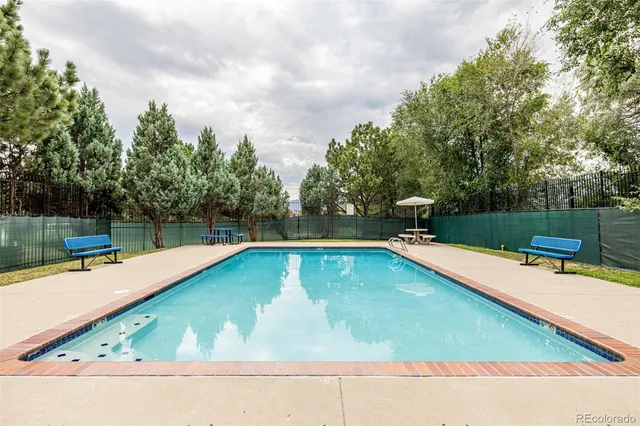 a small pool with lawn chairs and a table