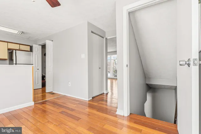 a view of a hallway with wooden floor and cabinet