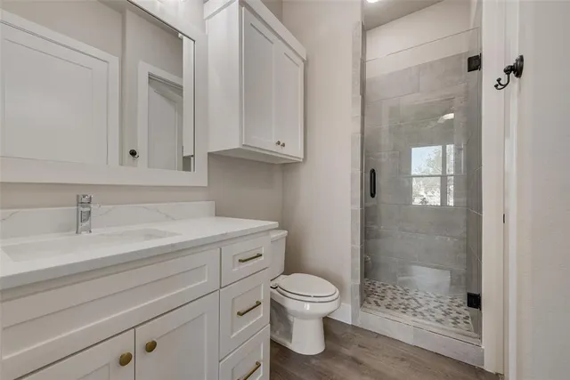 a bathroom with a granite countertop toilet a sink a mirror and shower
