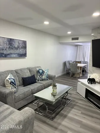 a living room with furniture a flat screen tv and kitchen view