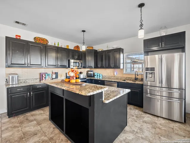a kitchen with stainless steel appliances granite countertop a sink a stove and a refrigerator