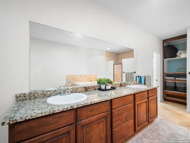 a bathroom with a granite countertop double vanity sink and a mirror