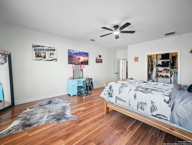 a bedroom with a bed and a dresser with wooden floor