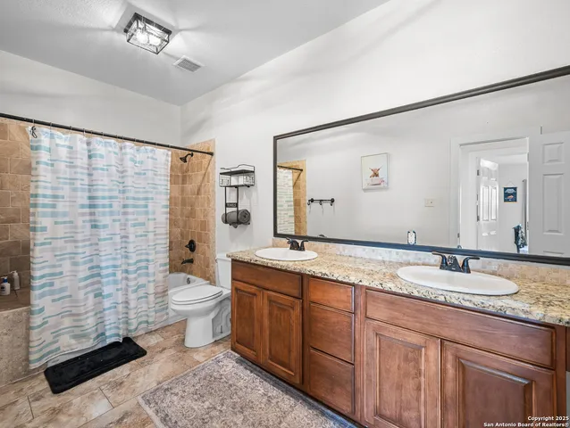 a bathroom with a granite countertop sink mirror vanity and toilet