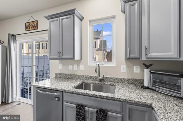 a kitchen with stainless steel appliances granite countertop a sink and cabinets with wooden floor