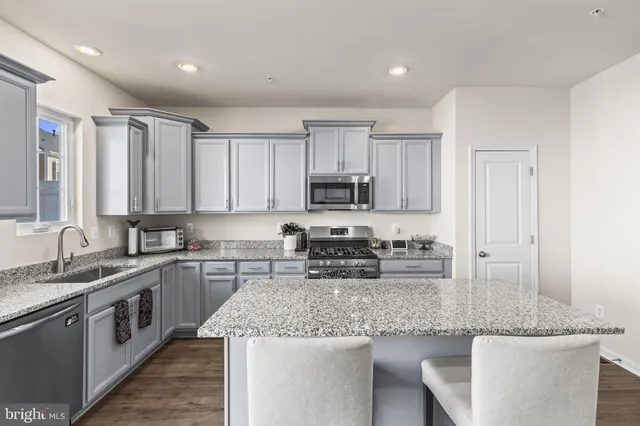 a kitchen with stainless steel appliances granite countertop a sink stove and cabinets
