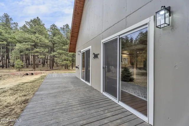 a view of wooden house with large trees and wooden fence