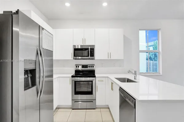 a kitchen with stainless steel appliances granite countertop a refrigerator sink and stove