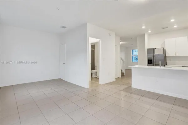 a view of an empty room and kitchen with window
