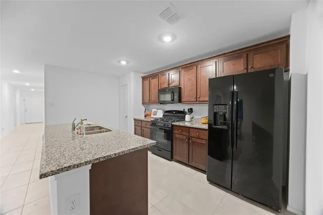a kitchen with granite countertop kitchen island stainless steel appliances a refrigerator sink stove microwave and cabinets