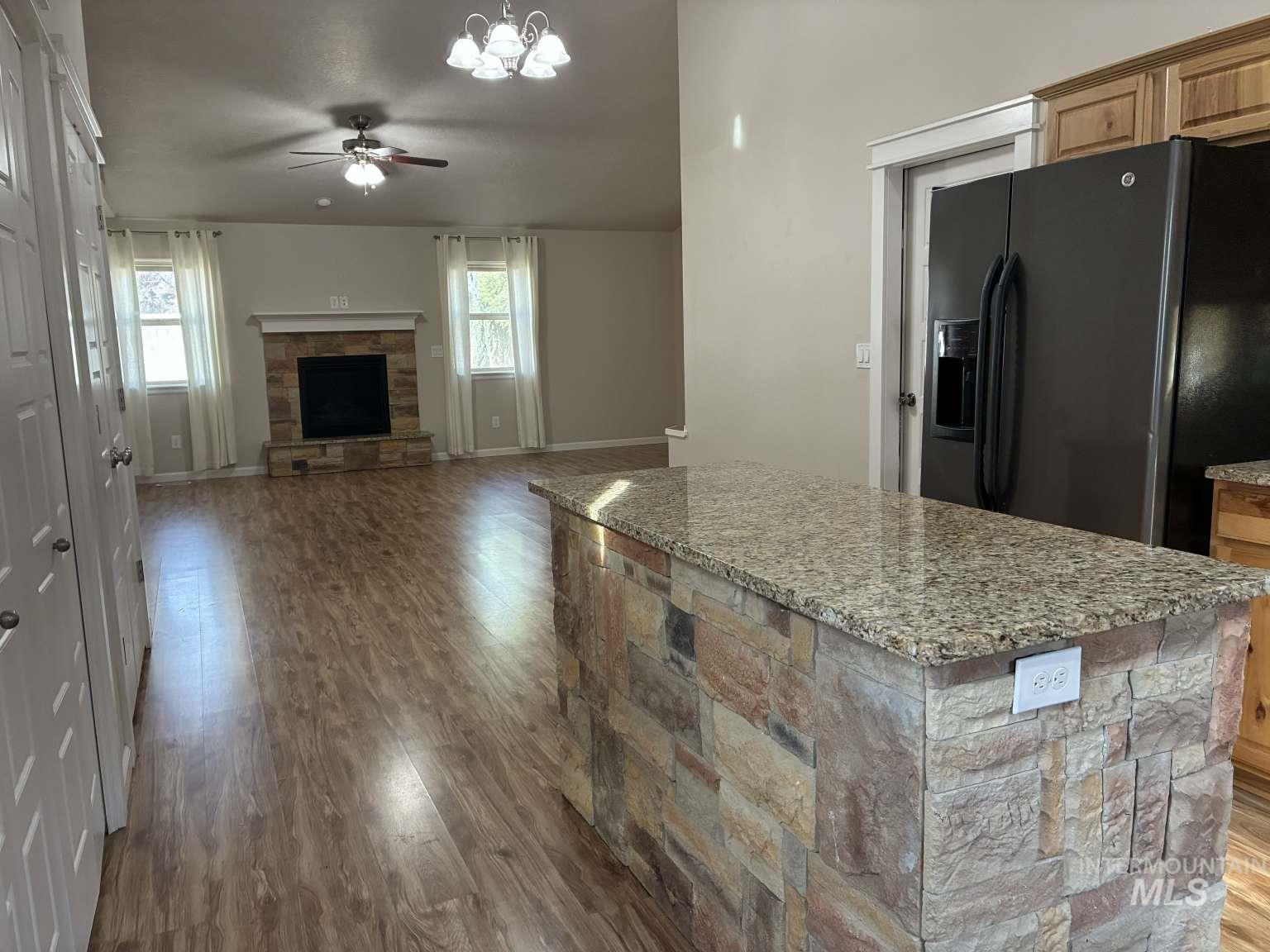 16439 North Driver Street Nampa, ID 83687 - Photo 12 of 13 Kitchen featuring black refrigerator with ice dispenser, ceiling fan, dark wood-style floors, a center island, and plenty of natural light