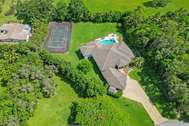 an aerial view of residential house with outdoor space and trees all around