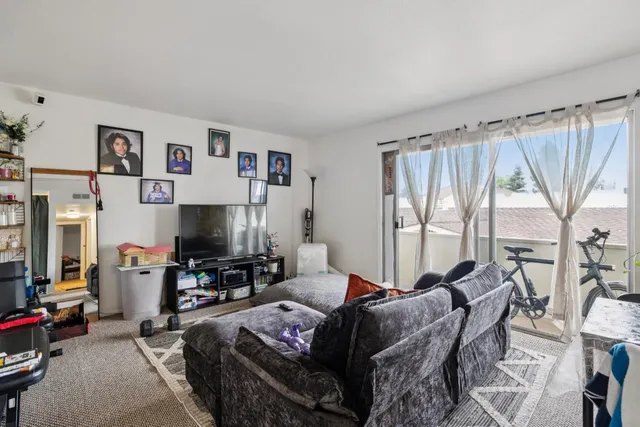 a living room with furniture a flat screen tv and a large window