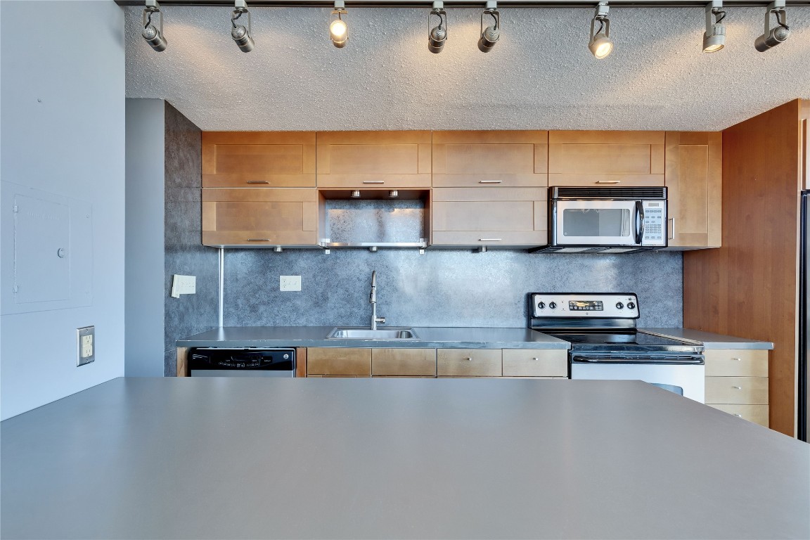 1801 Lavaca Street, Unit 5D Austin, TX 78701 - Photo 6 of 26 a kitchen with stainless steel appliances granite countertop a sink a stove and a microwave