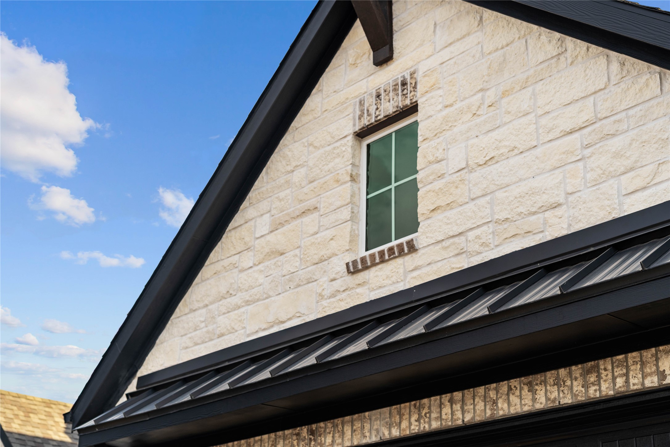 17020 Sweet Iris Court Conroe, TX 77302 - Photo 5 of 50 This striking gabled exterior showcases a sophisticated blend of textured cream-colored stone and rustic brick, all sharply framed by modern dark trim.