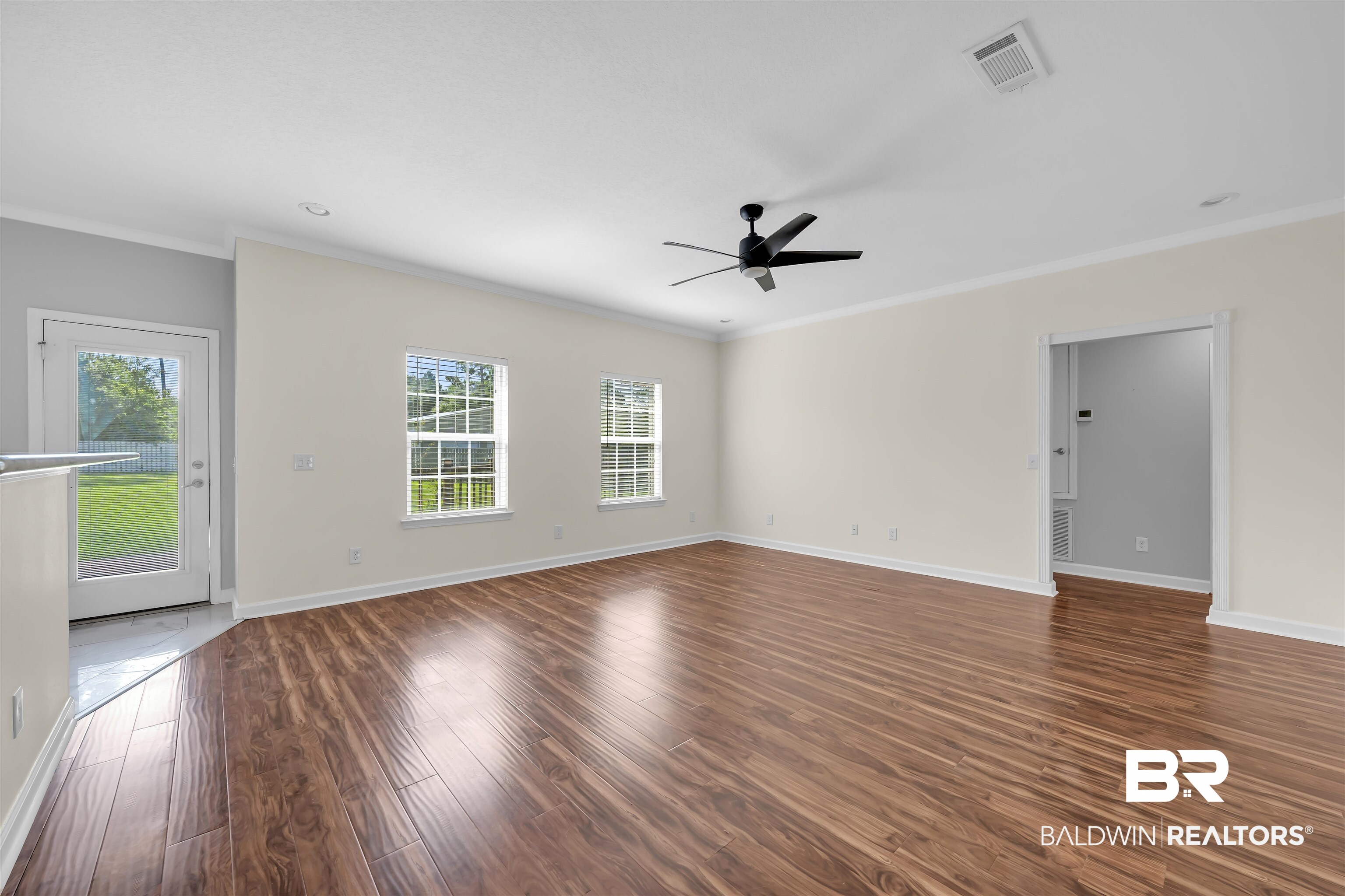 10147 Lyttleton Loop Lillian, AL 36549 - Photo 12 of 29 Spacious interior featuring wood-finish flooring, two large windows, a modern ceiling fan, and crown molding