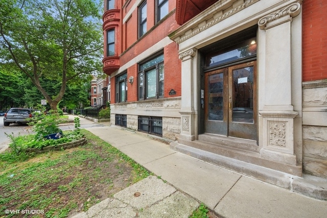 a front view of a building with garden and parking