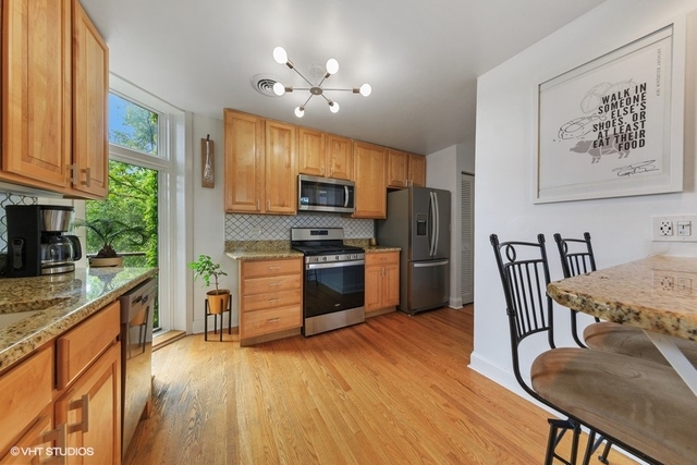 1049 West Altgeld Street, Unit 3A Chicago, IL 60614 - Photo 6 of 18 a kitchen with granite countertop a stove top oven a sink dishwasher a dining table and chairs with wooden floor
