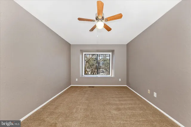 an empty room with a window and a ceiling fan