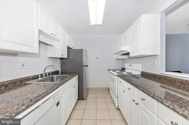 a kitchen with granite countertop a sink stove and cabinets