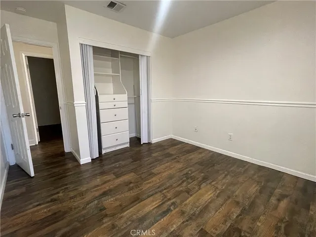 an empty room with wooden floor and cabinet