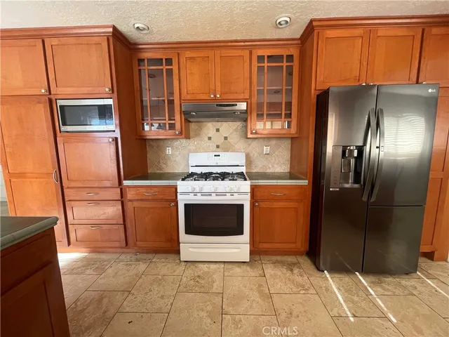 a kitchen with stainless steel appliances granite countertop a refrigerator and a stove top oven