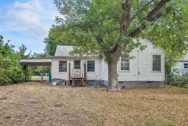 a view of a house with backyard and a tree