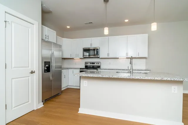 a kitchen with stainless steel appliances granite countertop a refrigerator a sink a stove and oven with wooden floor