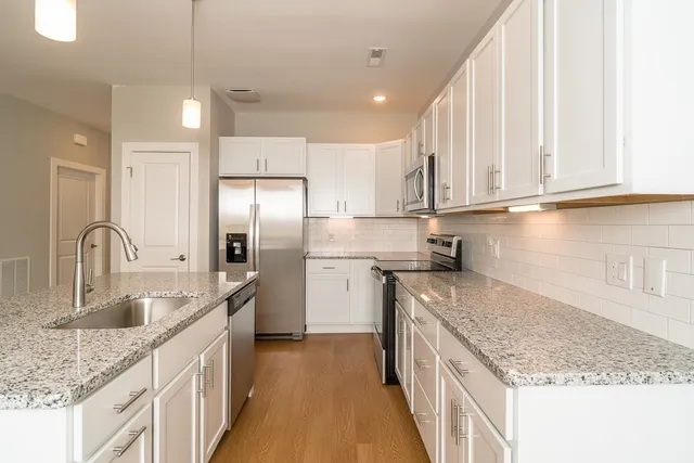 a kitchen with stainless steel appliances granite countertop a sink stove and refrigerator