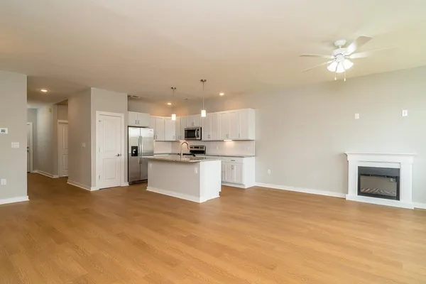a view of kitchen with kitchen island a sink dishwasher a refrigerator and white cabinets with wooden floor