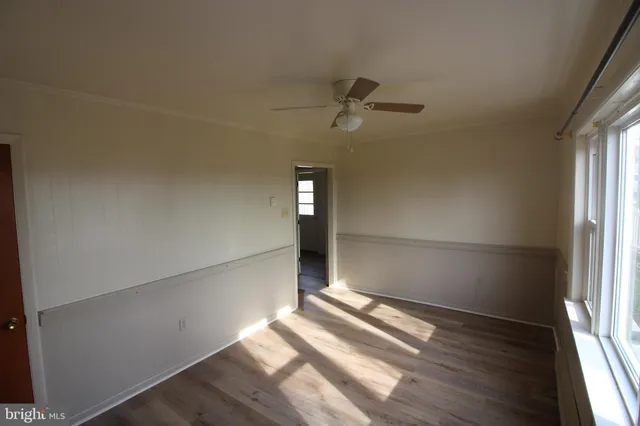 a view of empty room with wooden floor and fan